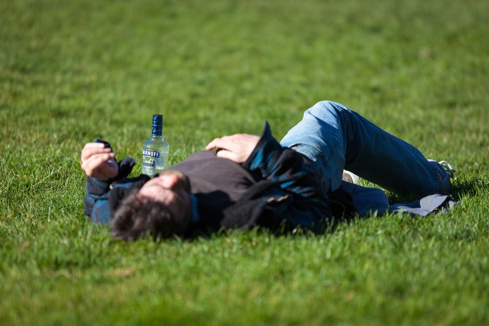 맥주 한 병을 들고 풀밭에 누워 있는 남자