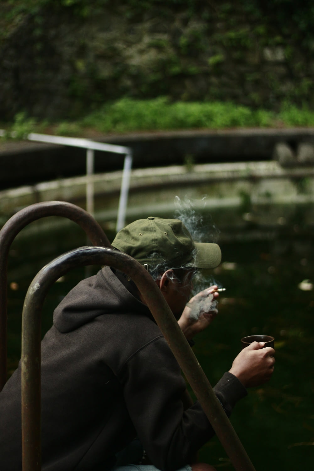 man sitting while having coffee and smoking between rails