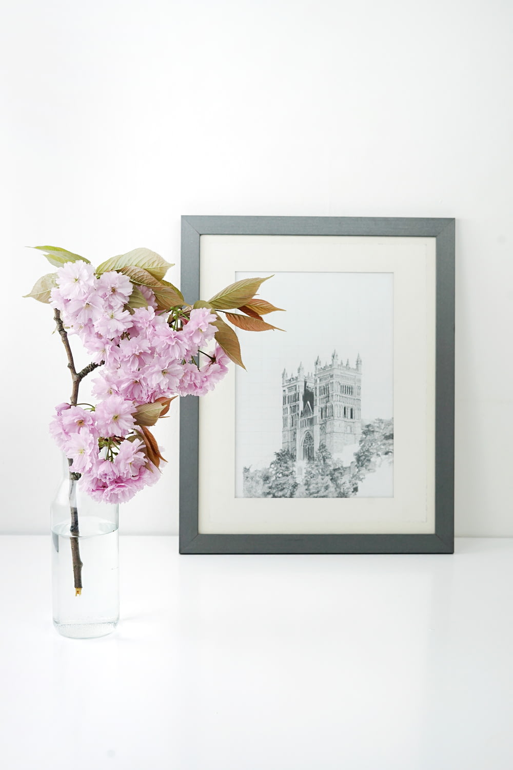 marco de fotos rectangular de madera gris junto a flor rosa
