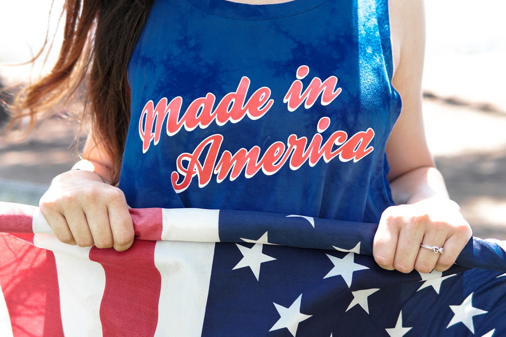 mujer en blusa azul sin mangas sosteniendo la bandera de América