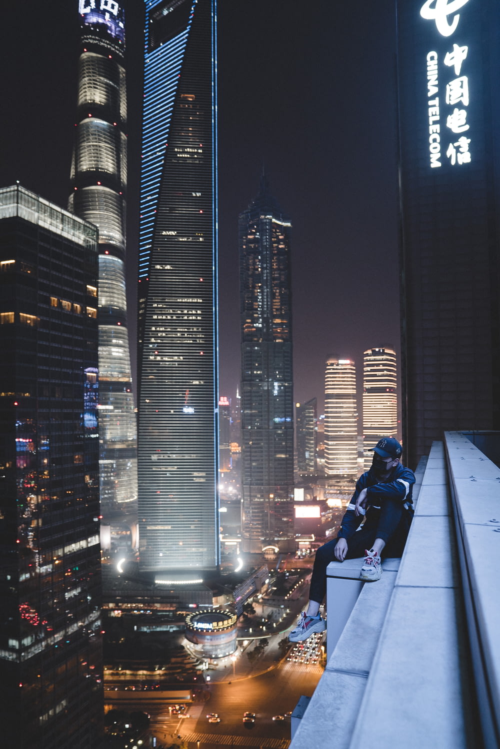 man sitting on building gutter during nighttime