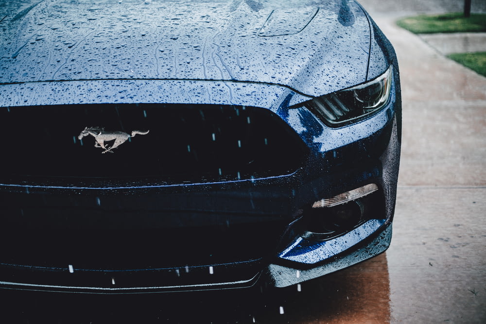 Die Vorderseite eines blauen Mustangs, der am Straßenrand geparkt ist