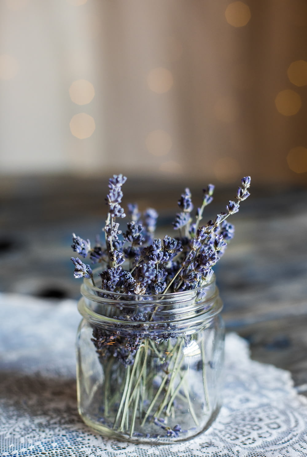 Fotografia a fuoco selettiva di fiori dai petali blu in un barattolo di vetro trasparente