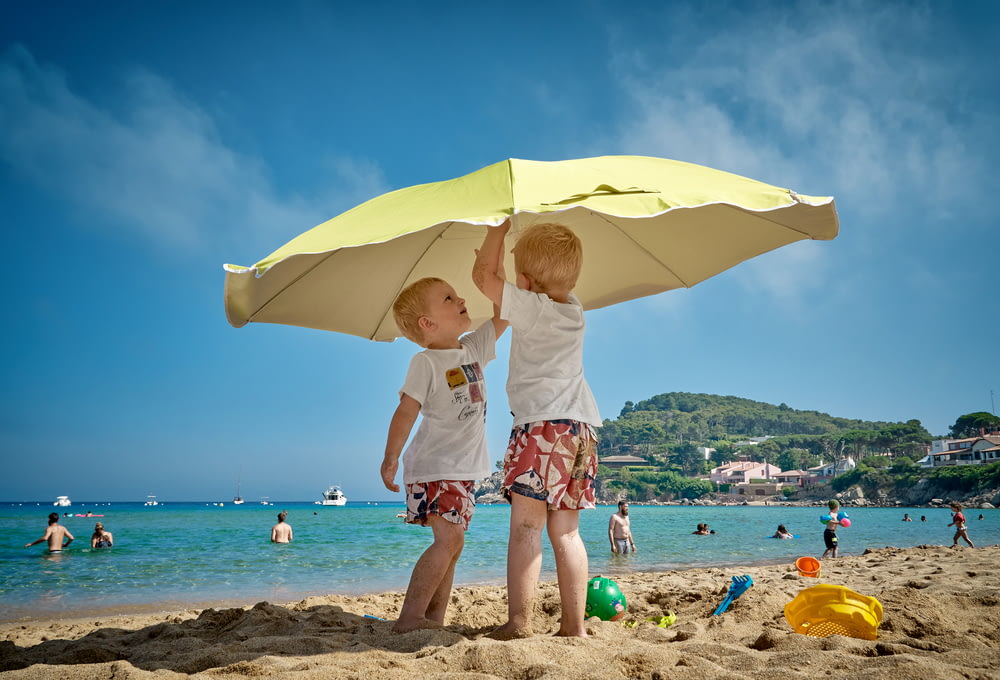 Dos niños jugando bajo la sombrilla en la orilla del mar
