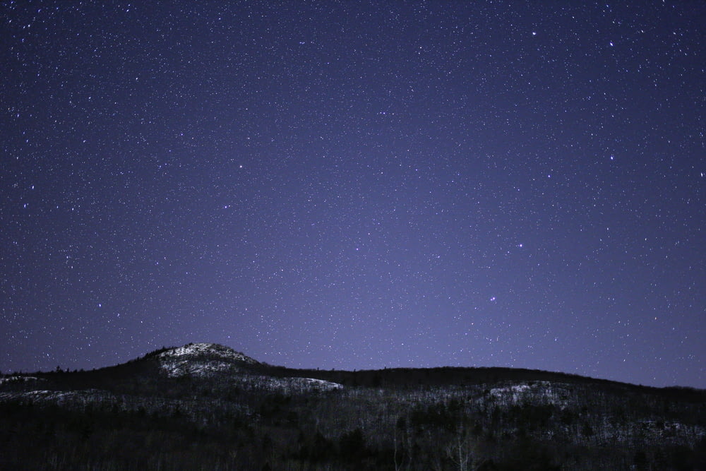 silhouette of mountain against stars