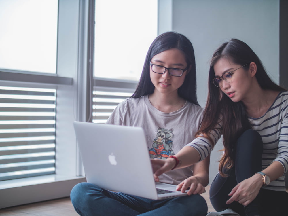 Zwei Frauen diskutieren miteinander, während sie auf einen Laptop schauen