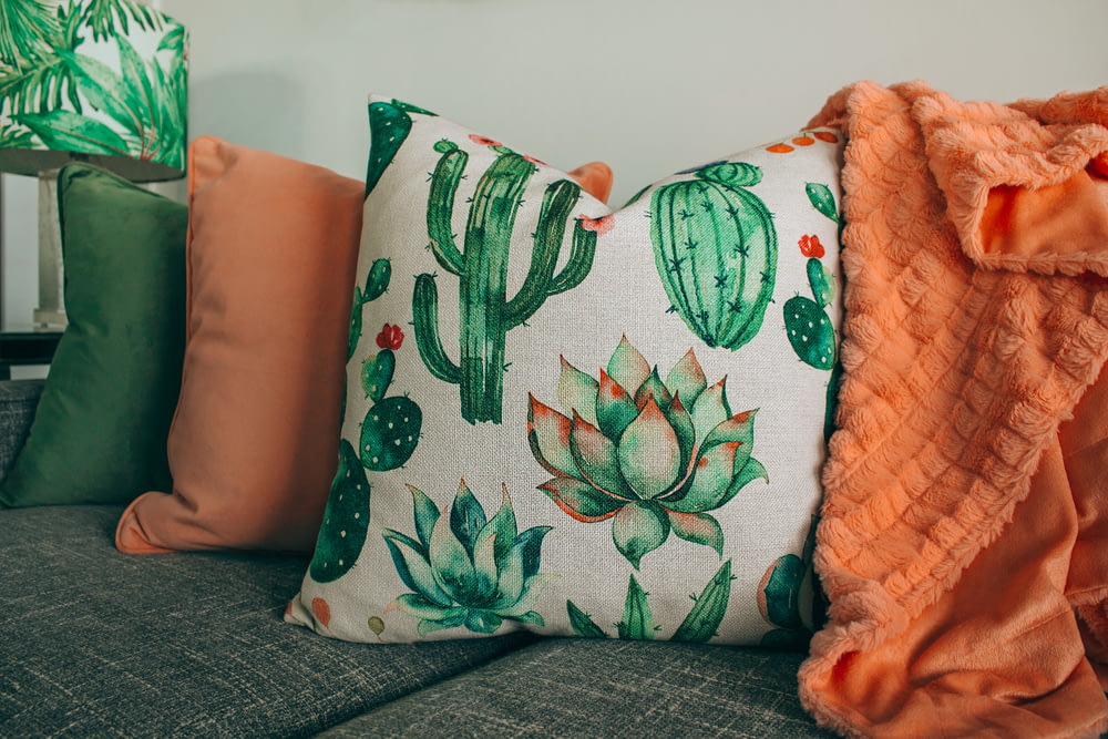 three green, orange, and white throw pillows on sofa