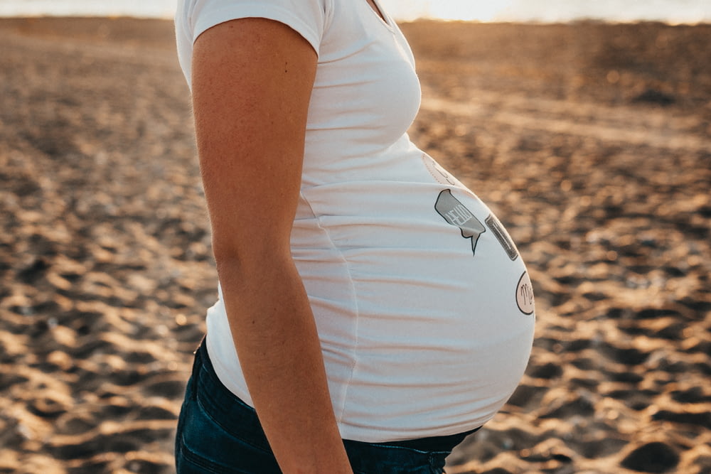 donna incinta in piedi sulla sabbia