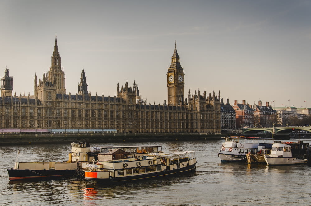 quattro barche bianche che viaggiano sul fiume accanto al Big Ben a Londra