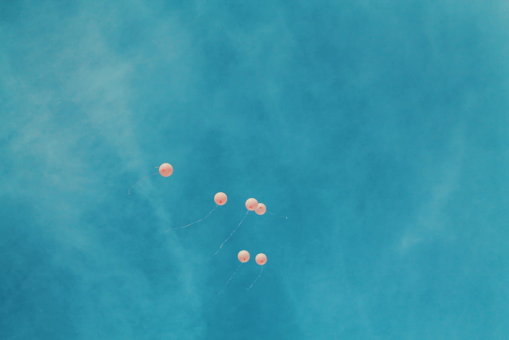 Blick aus einem niedrigen Winkel auf sechs orangefarbene Ballons bei blauem Himmel