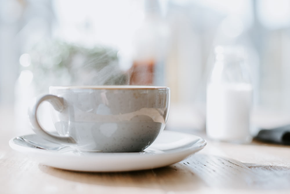 tazza da tè in ceramica bianca su piattino rotondo bianco