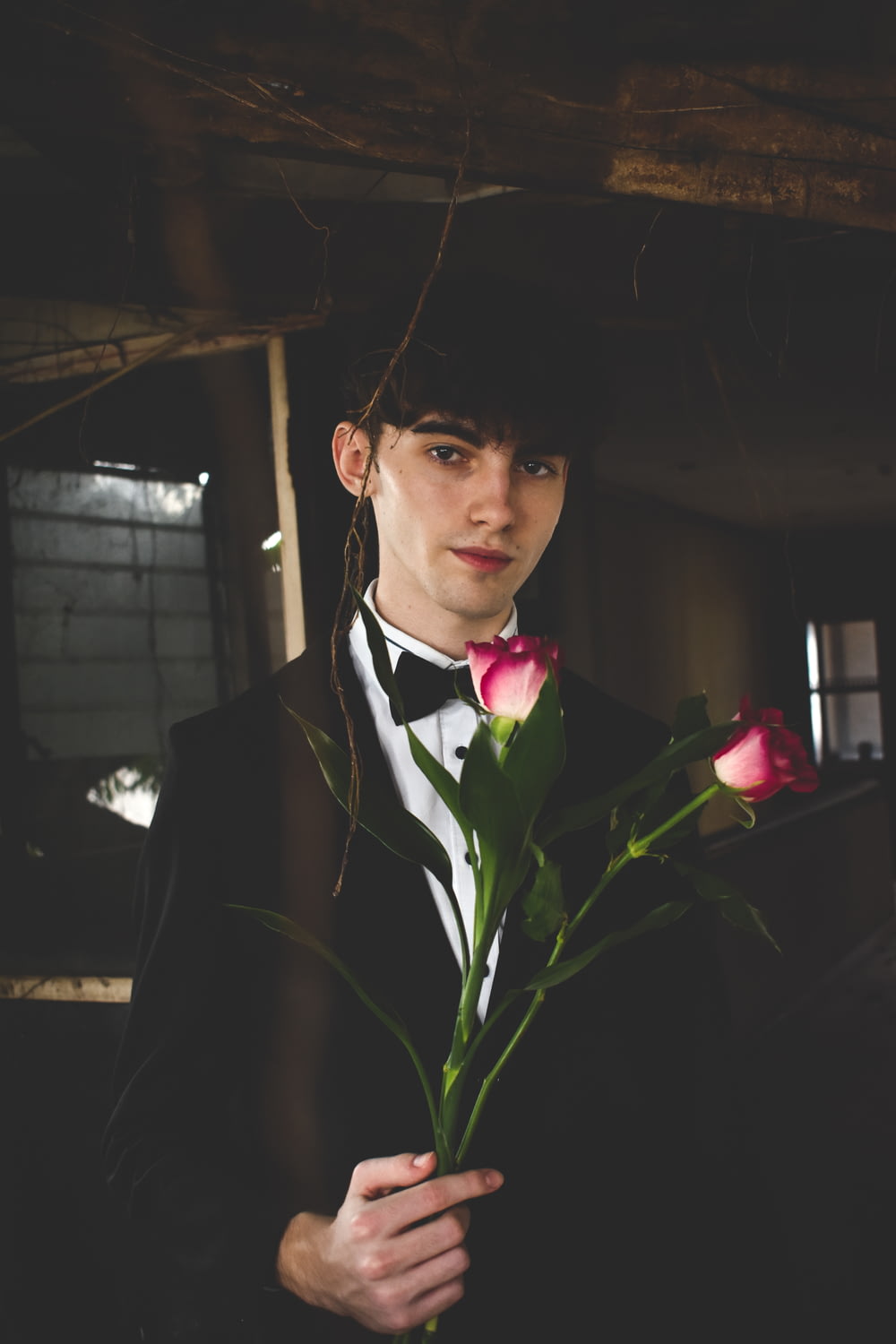 Mann in schwarz-weißem Anzug mit zwei roten Rosen
