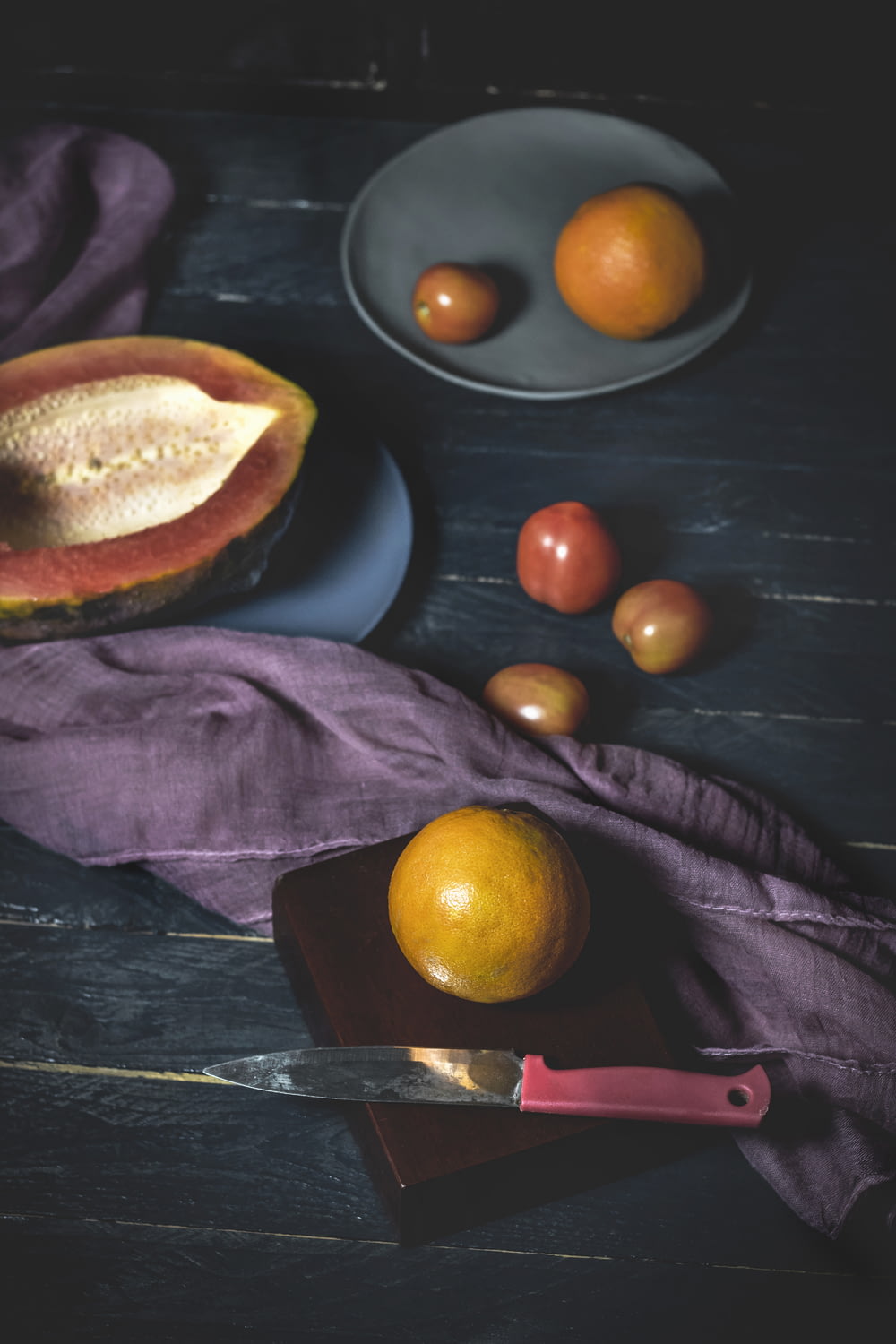 fruits near red and gray knife on wood