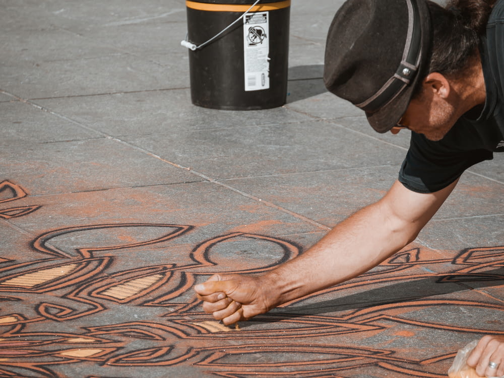 床に砂のアートワークを作る男性