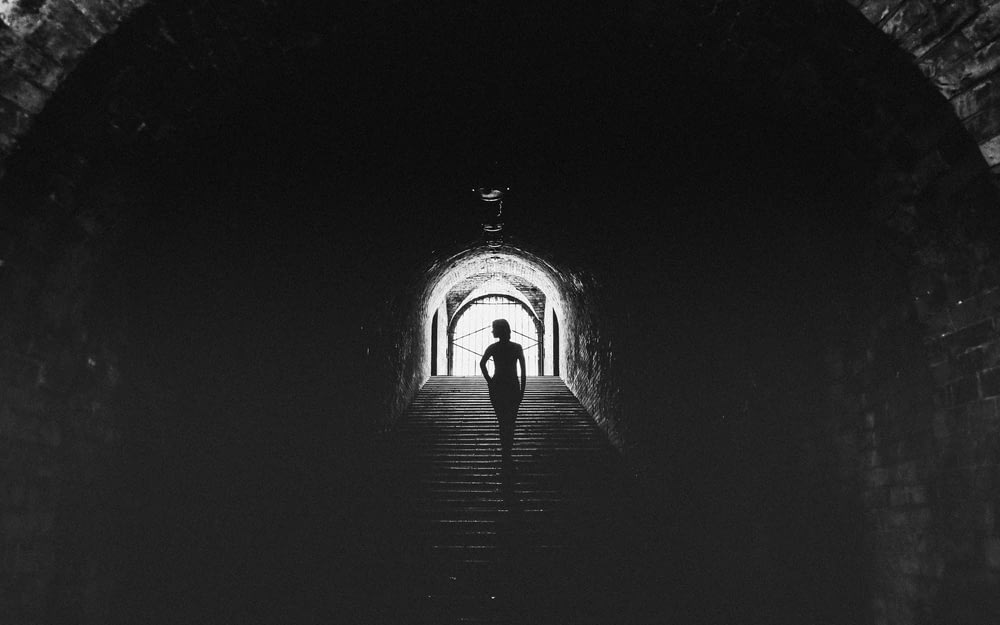 最後に光が灯る暗いトンネルを歩いている人