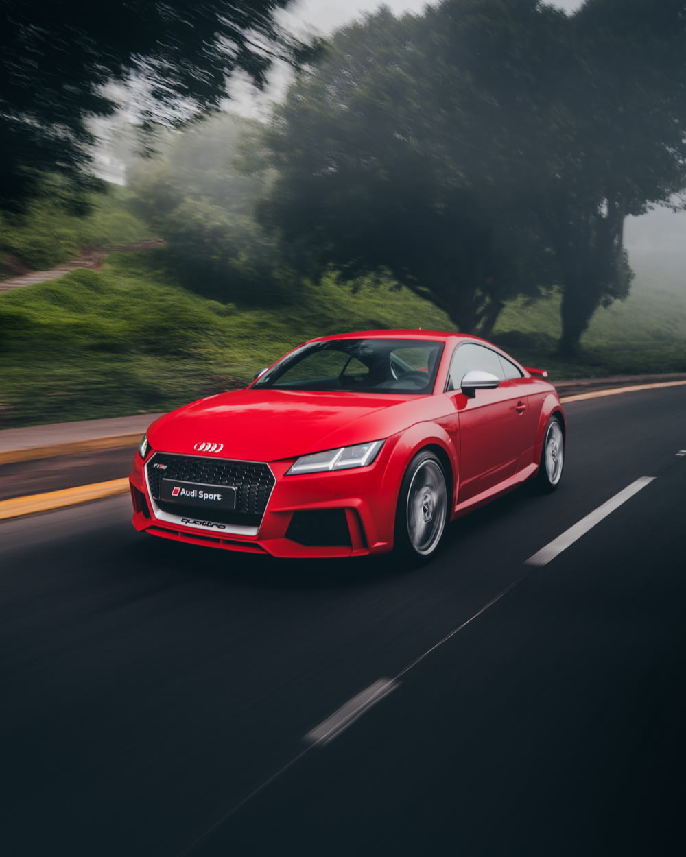red Audi coupe on road near trees at daytime