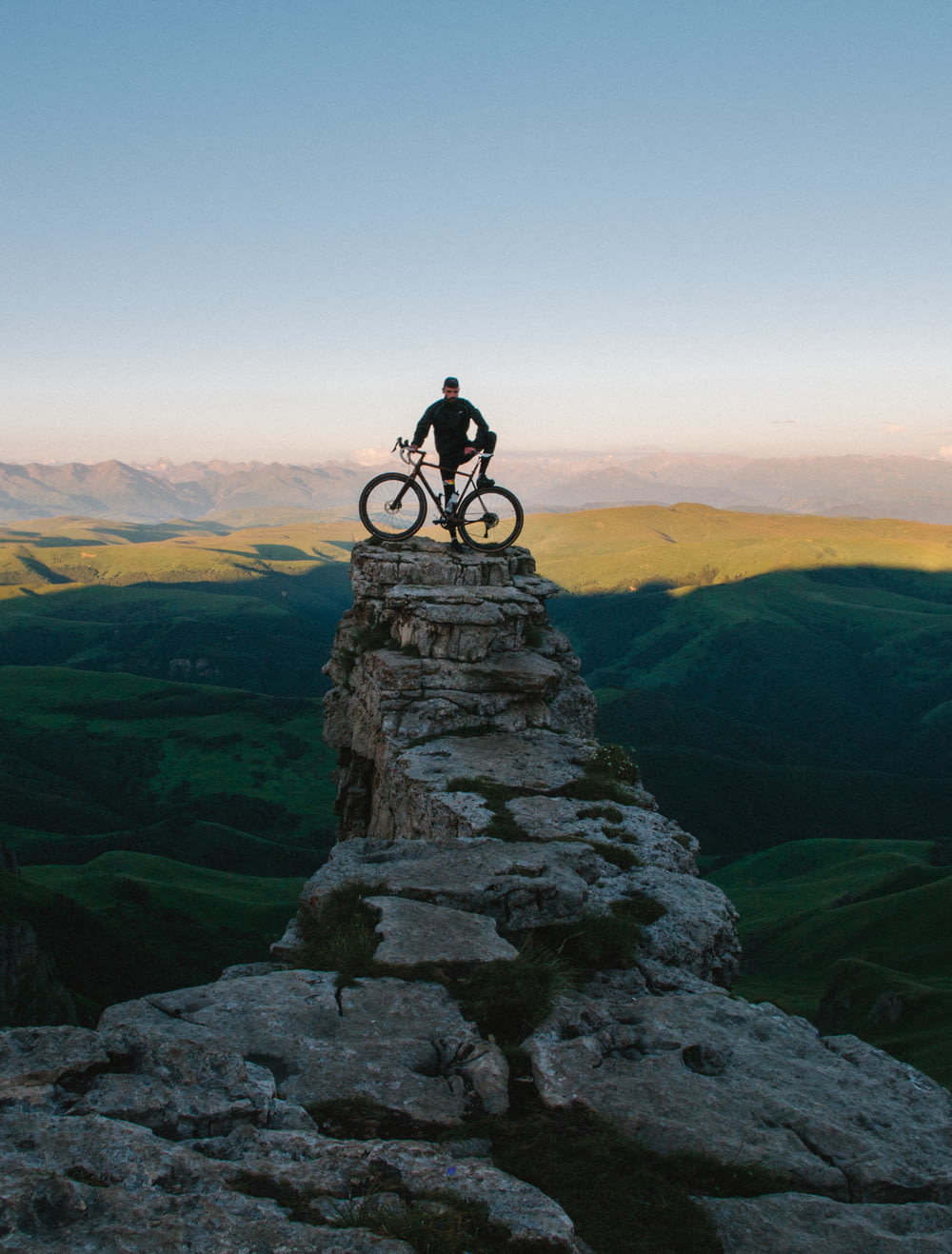 hombre sosteniendo la bicicleta mientras está de pie en la montaña gris
