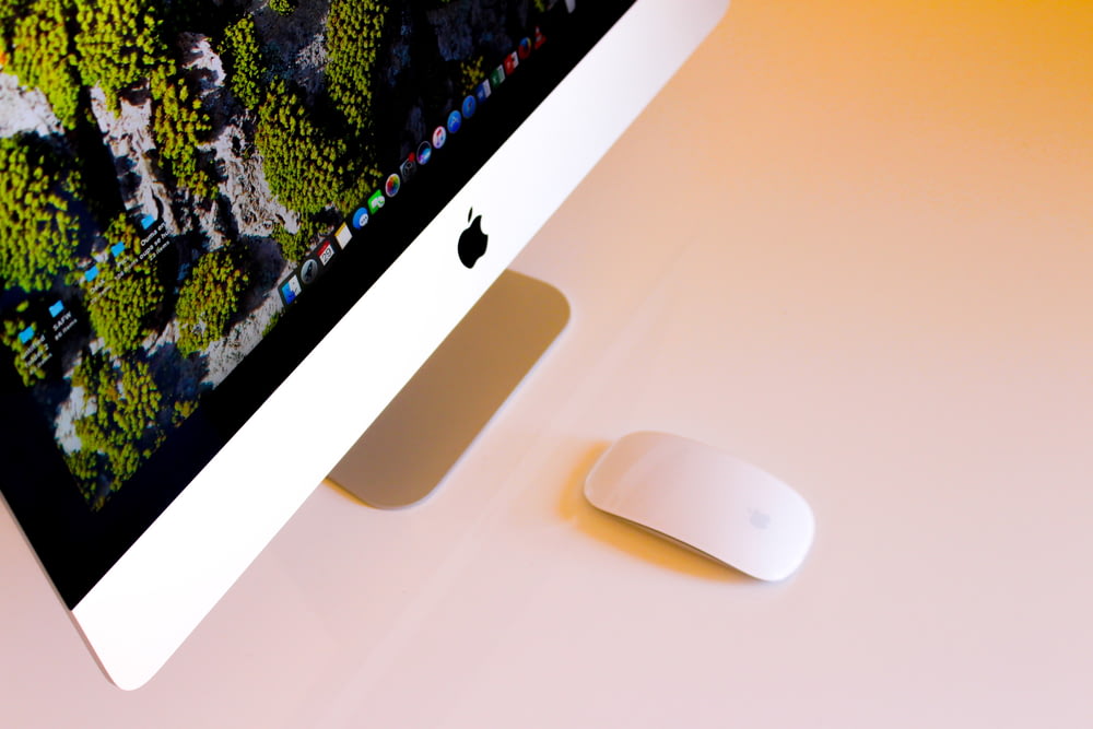 turned-on silver iMac beside Apple Magic Mouse