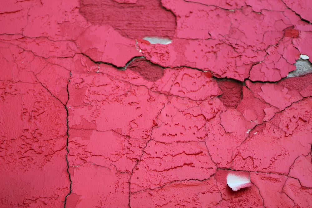 a close up of a red wall with peeling paint