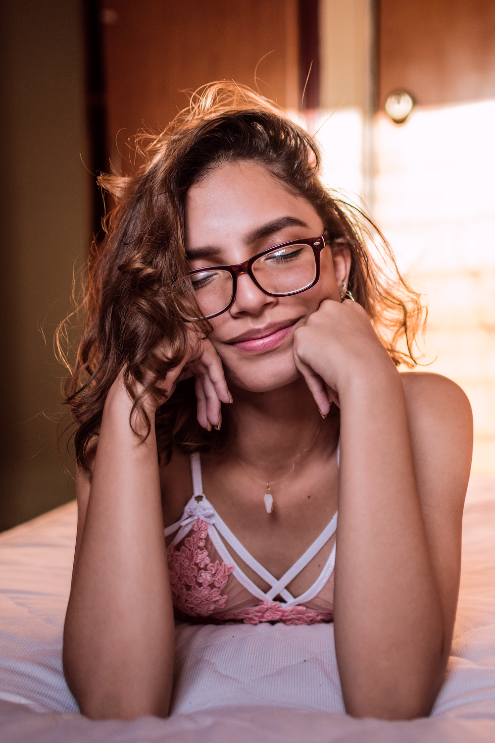 a young woman wearing glasses laying on a bed