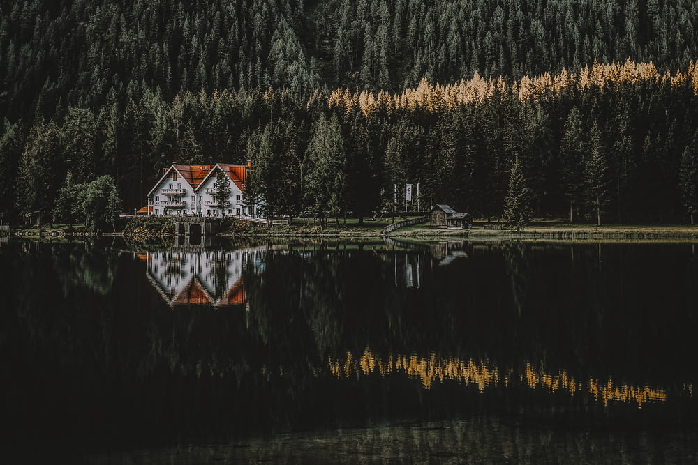 Casa branca e marrom com reflexo na água cercada de árvores