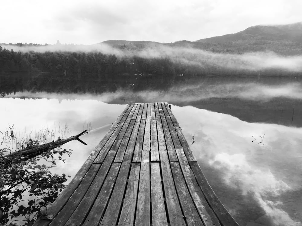 grayscale photography of dock beside body of water