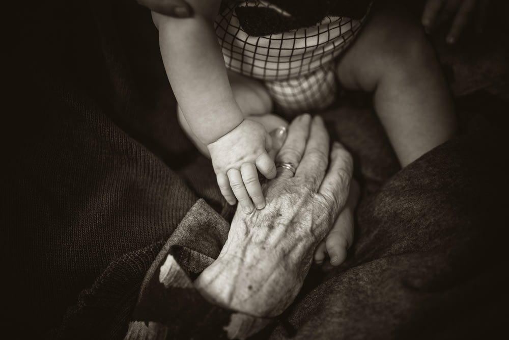 une femme âgée tenant la main d’un bébé