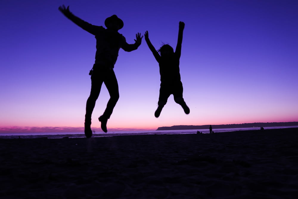 silhouette of two people jumping