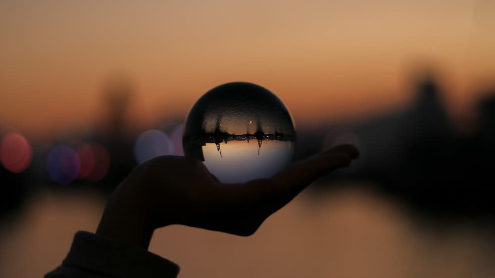 person holding glass ball in selective focus photography