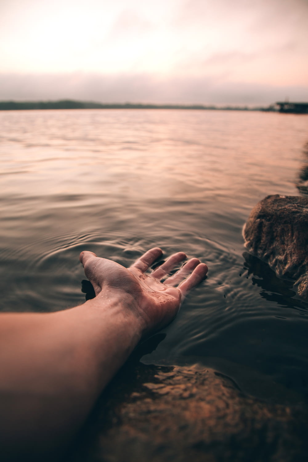 fotografía de enfoque selectivo de la mano de la persona en el cuerpo de agua