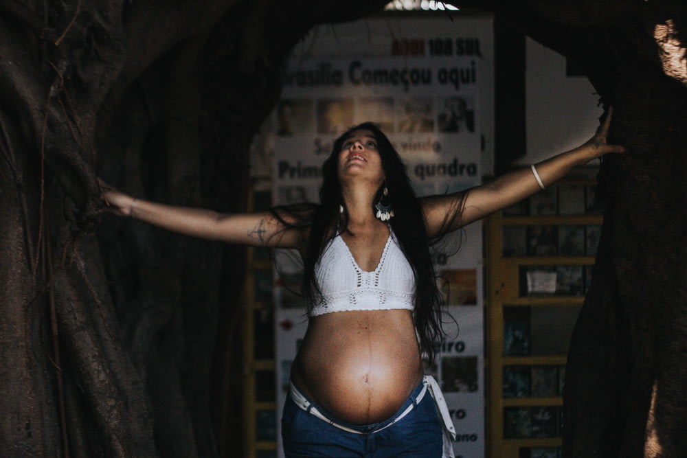 a pregnant woman standing in a tree tunnel
