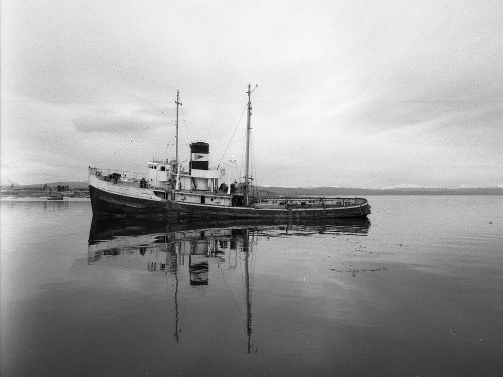 grayscale photo of fishing vessel on body of water