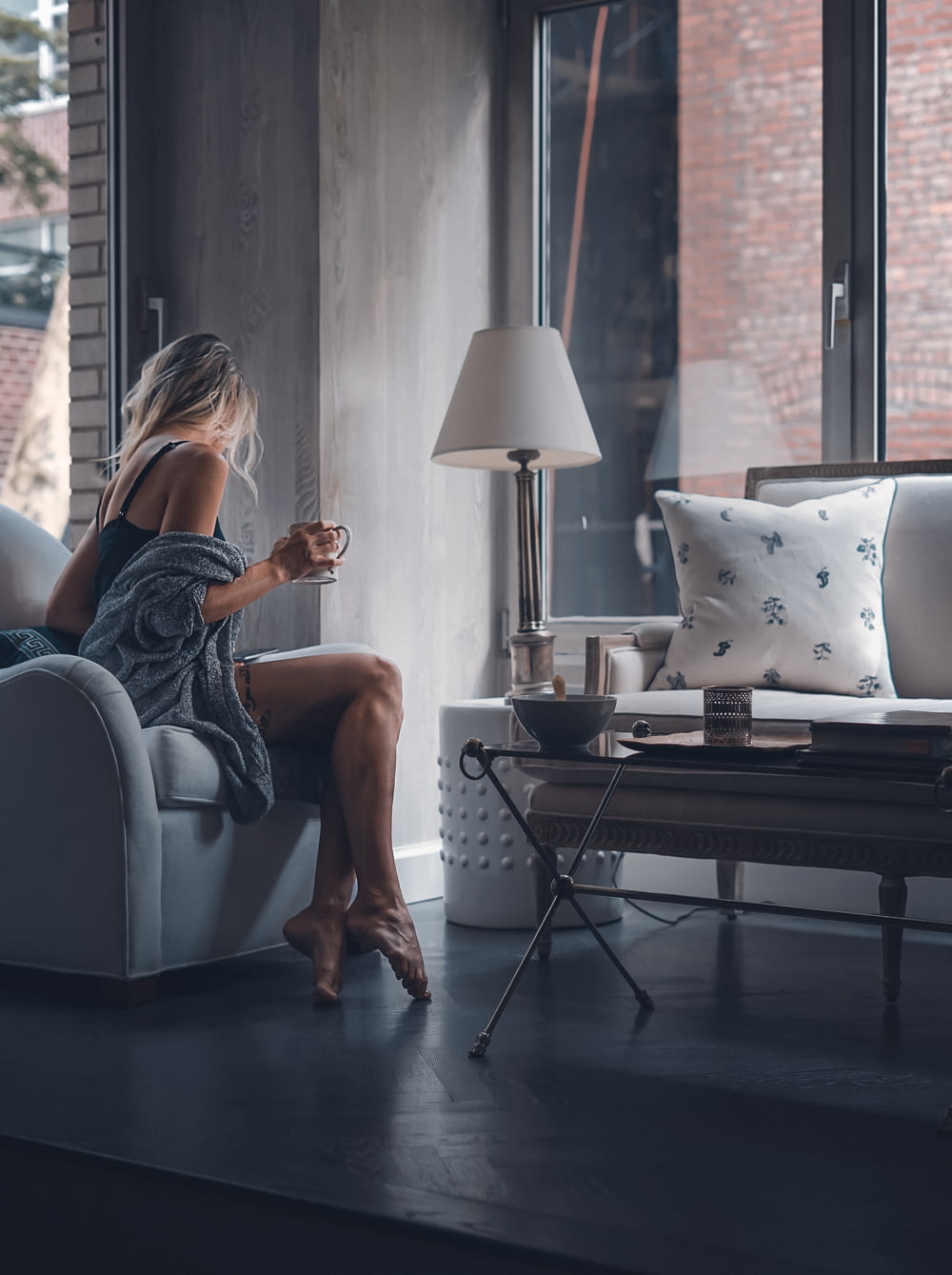 femme assise sur une chaise de canapé gris tenant une tasse