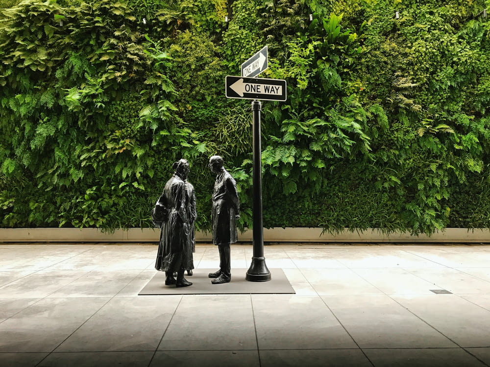 three statues beside one-way road signage during daytime