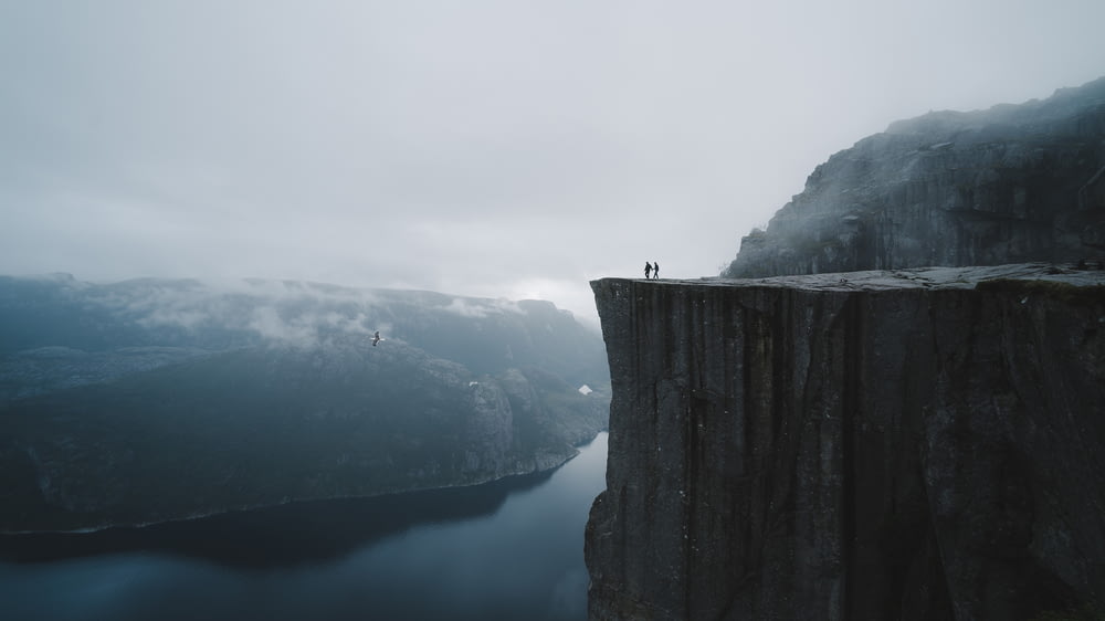 two people standing on edge of cliff at daytime