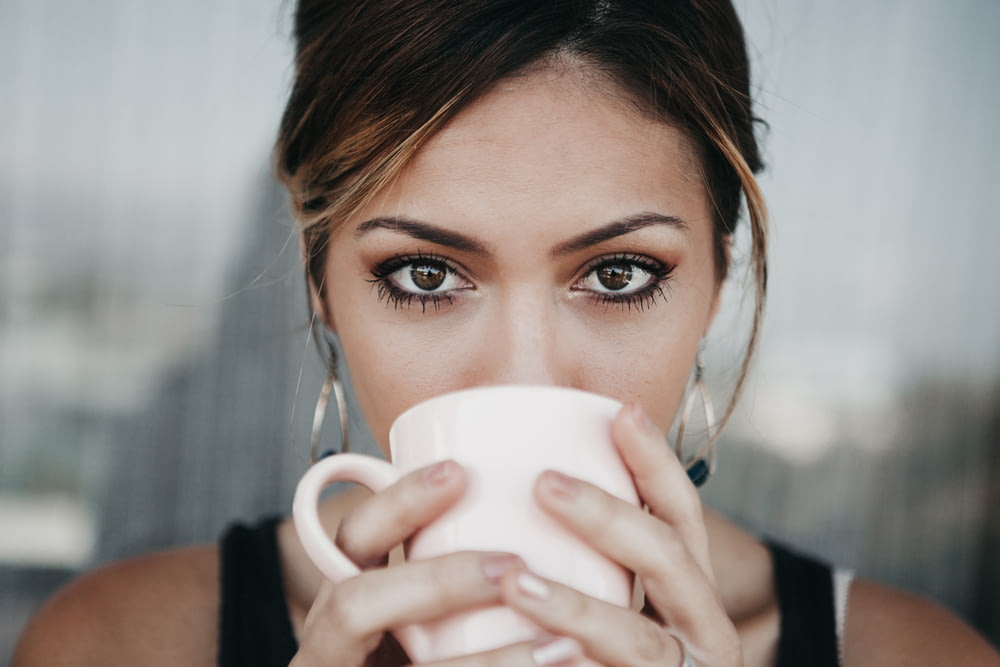 donna che beve dalla tazza di caffè bianco
