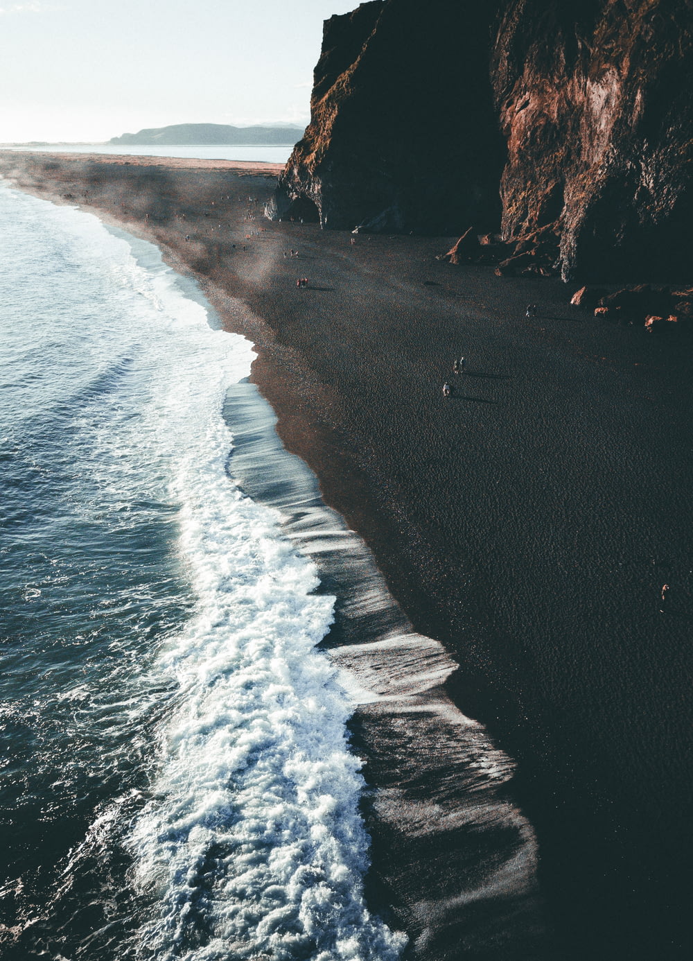 a black beach with waves coming in to the shore