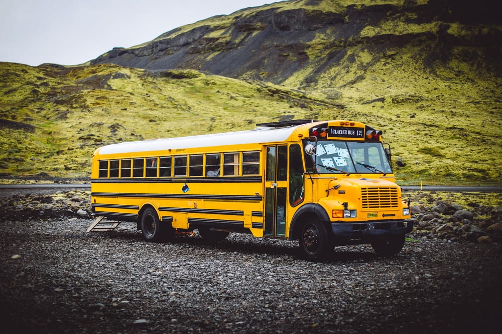 yellow school bus parked near green mountain