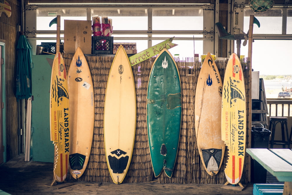 Sechs verschiedenfarbige Surfbretter auf braunem Brett