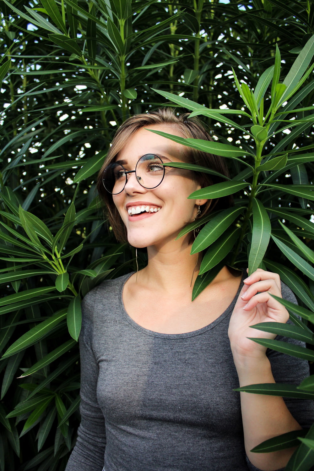 woman holding a green-leafed plant smiling during daytime