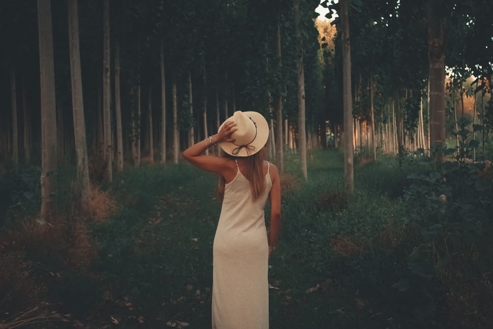 woman in white spaghetti strap dress near trees