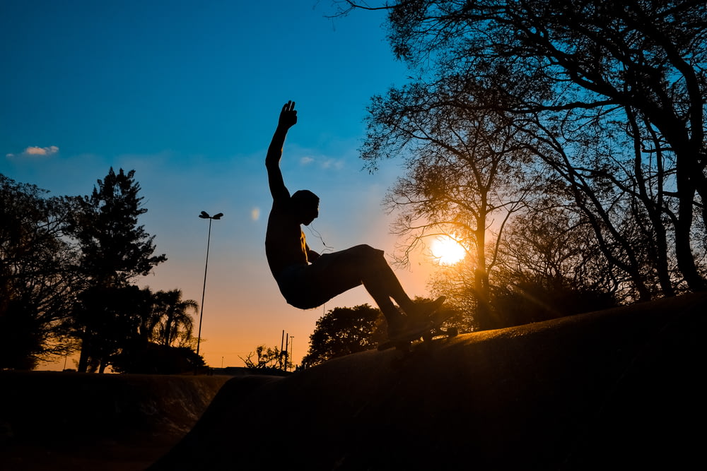 silhouette of man riding on skateboard during sunset