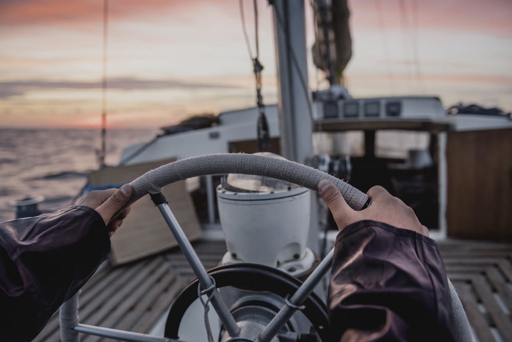 selective focus photography of person grabbing on boat steering wheel