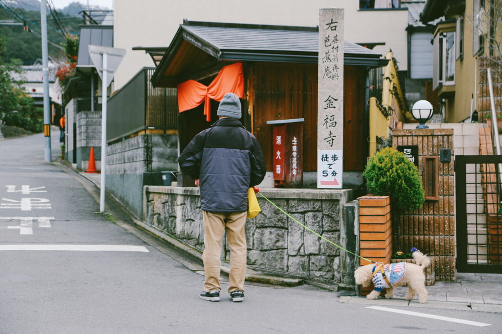 man with dog walking on street during daytime