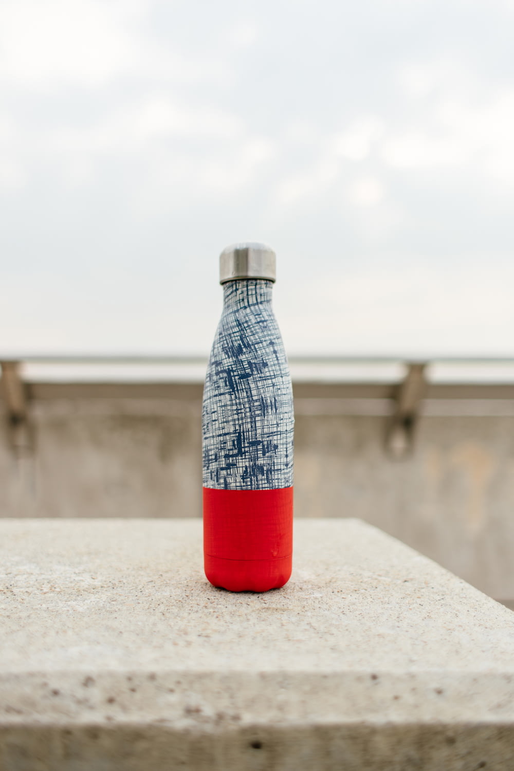 gray and red bottle on white concrete surface