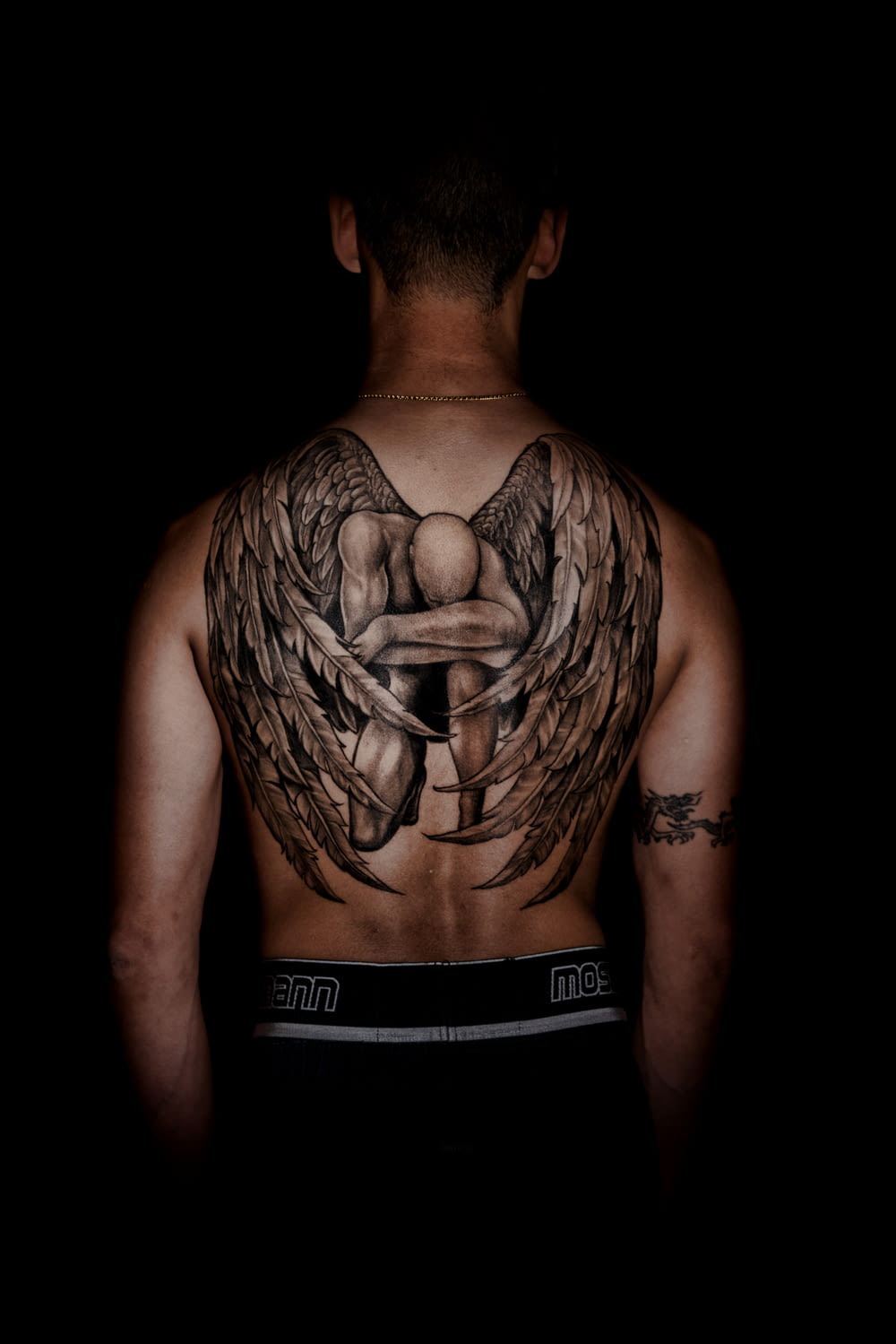 person with kneeling angel back tattoo