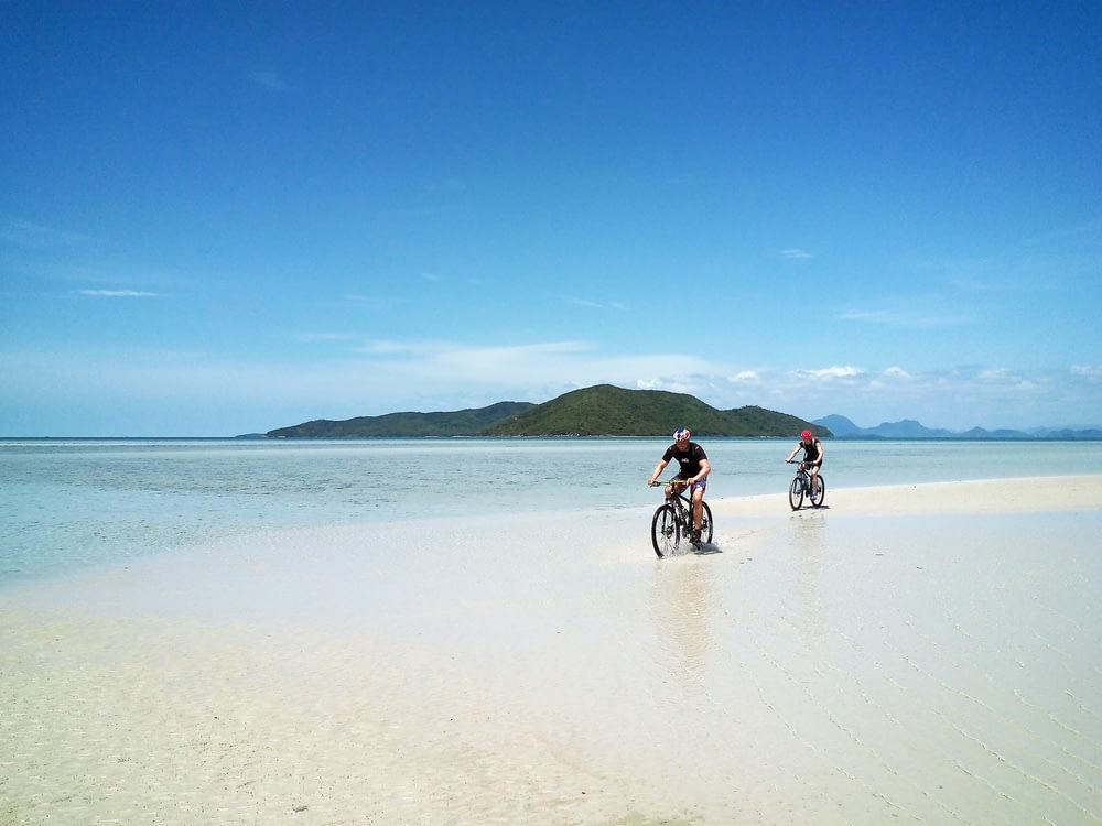 two men riding bicycle on the beach
