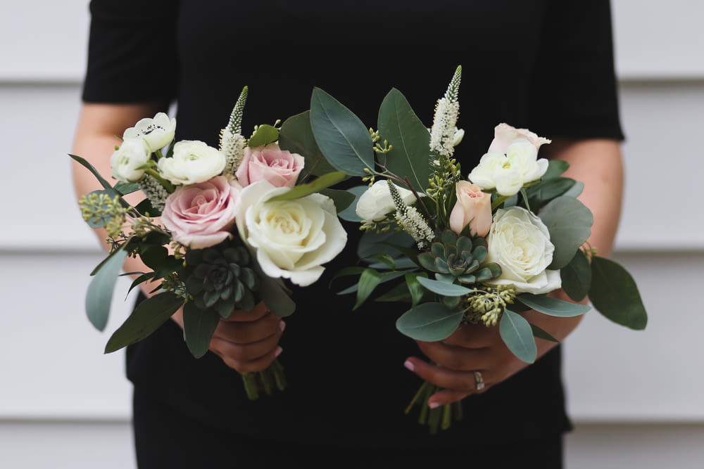 selective focus photography of person holding white and pink hybrid tea rose flowers bouquet