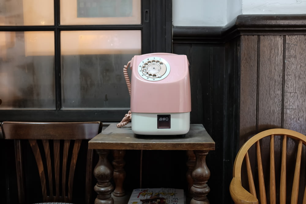 pink and white telephone on brown table
