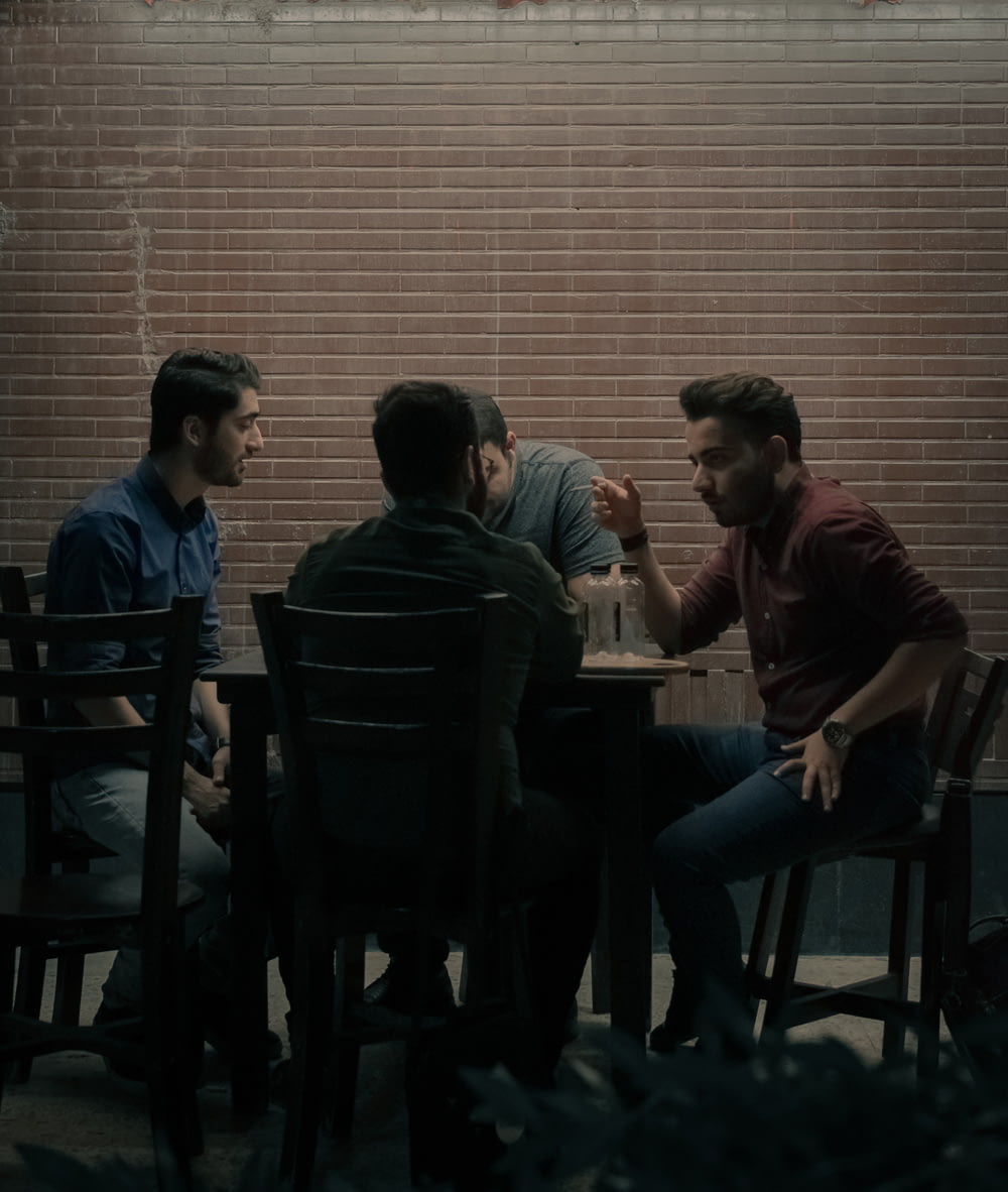 quatre hommes assis à côté d’une table
